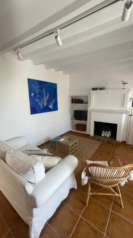 salón con cuadro, chimenea y silla de mimbre