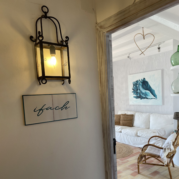 farolillo alumbra cartel de habitación ifach y se ve salón tras marco de puerta